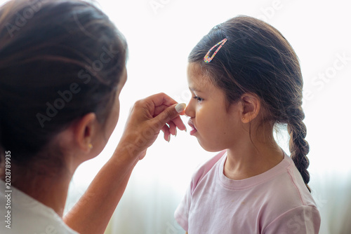 Fotografie Niña tomando jarabe pediátrico con cuchara medidora