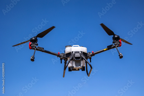 Bild auf Leinwand An unmanned aerial vehicle configured for agricultural spraying operations hover