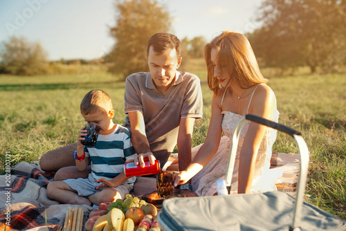 Fotografija Young family members bond while enjoying a relaxing outdoor picnic in a vibrant