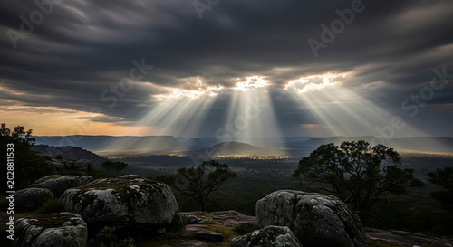 Dramatic Sunlight Breaking Through Clouds Over Rocky Landscape