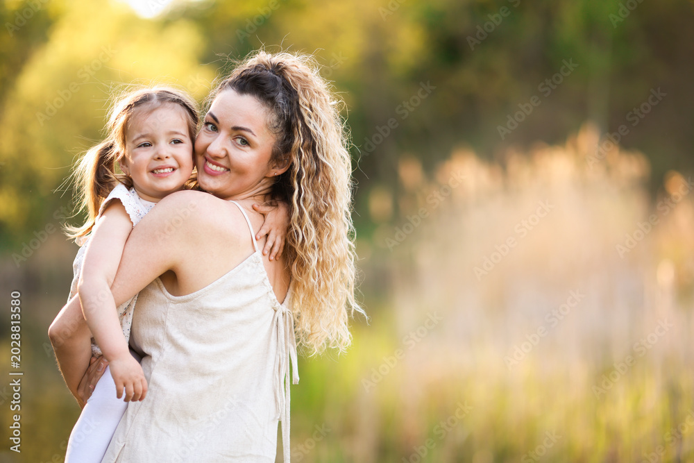 Fototapeta premium Mother with her cute little daughter in nature. Space for text