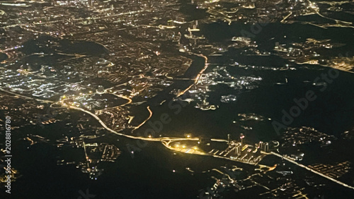 Night aerial city lights view from airplane window during flight