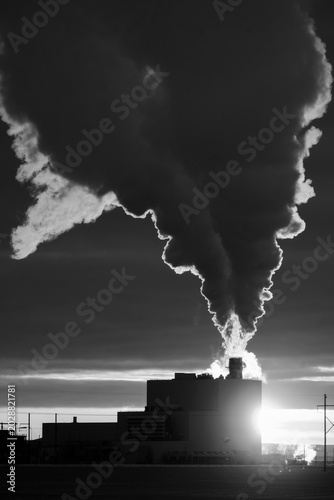 Industrial smokestack billowing thick dark smoke against a dramatic sky