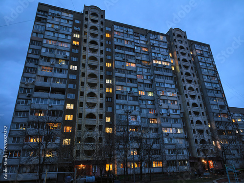 Residential building illuminated at night, city lights reflecting from glowing windows