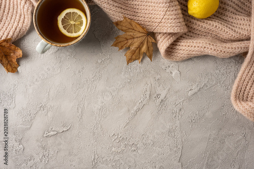 Obraz na plátně Autumn cozy tea with lemon and knit sweater on textured concrete table with drie