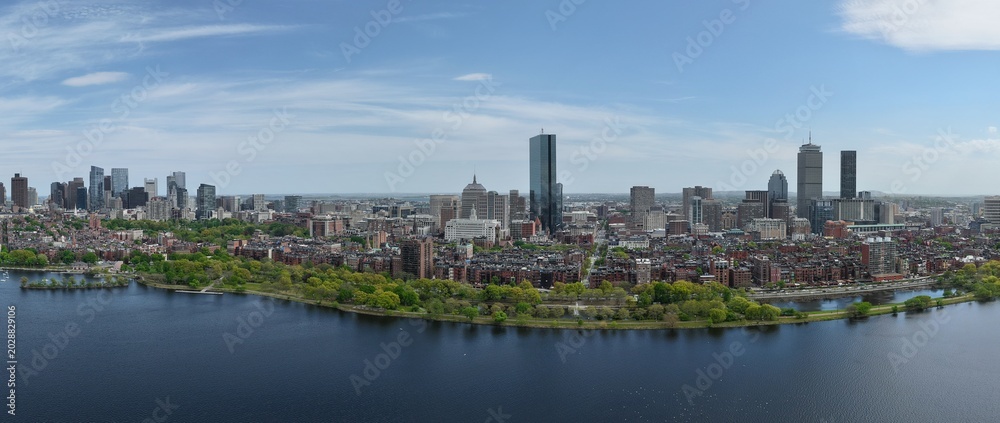 Fototapeta premium Panoramic aerial drone view of Boston Back Bay skyline, Prudential Tower, and Charles River Esplanade on a clear summer day, featuring historic brownstones and city skyscrapers, USA.