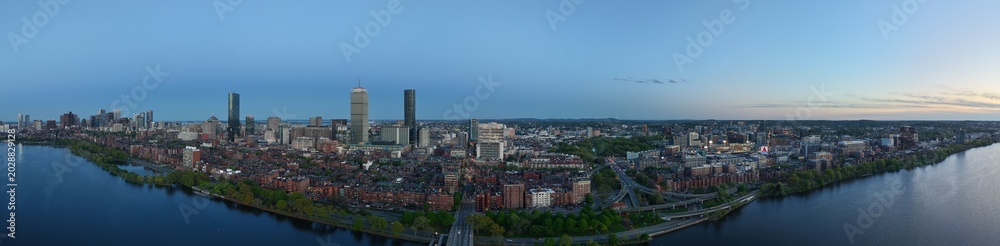 Fototapeta premium Panoramic aerial drone view of Boston Back Bay skyline, Prudential Tower, and Charles River Esplanade on a clear summer day, featuring historic brownstones and city skyscrapers, USA.