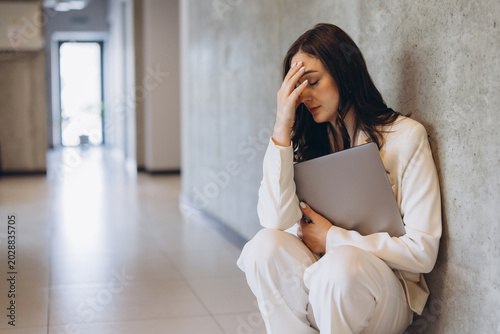Foto Stressed businesswoman experiencing professional burnout and headache, sitting o