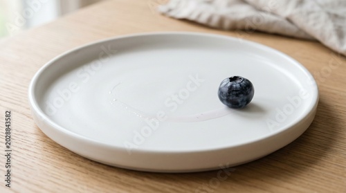A single blueberry on a white plate, ready to be eaten