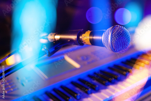 Cuadro en lienzo Micrófono azul de escenario sobre teclado de piano con luces bokeh de colores, concepto de actuación musical en vivo