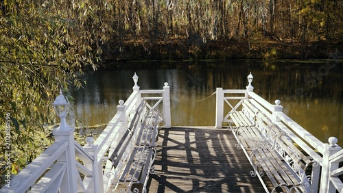 Bilde på lerret Serene view of a white wooden pier with benches on a tranquil lake