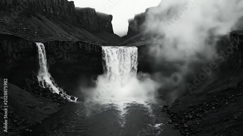Epic Black and White Waterfall Cascade Flowing into River with Rocky Terrain and Dramatic Mist