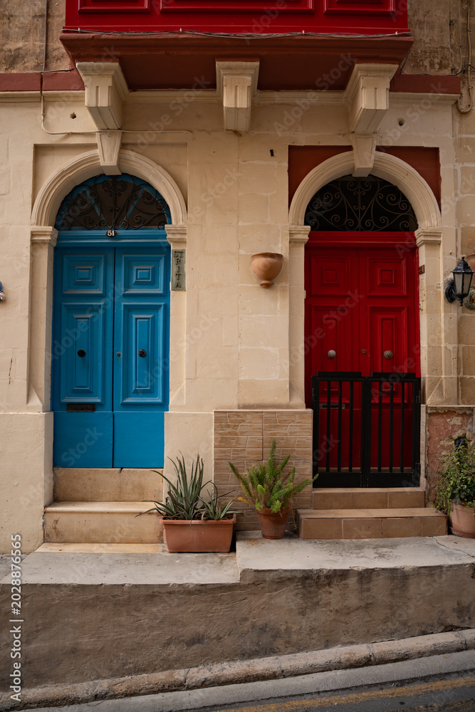 Fototapeta premium Epic Malta traditional blue wooden door ancient architecture vertical panorama. Cinematic view of historic limestone house facade, classic stone portal frame, brass door knockers and vintage iron la