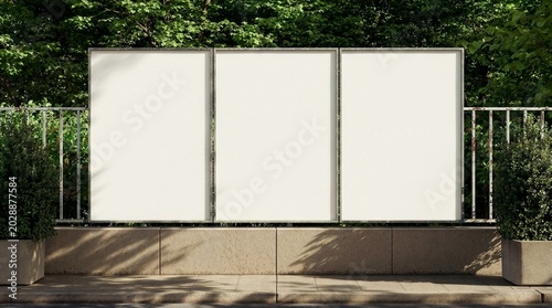 Bild auf Leinwand A set of three empty vertical poster frames mounted on a concrete fence with green trees in the background