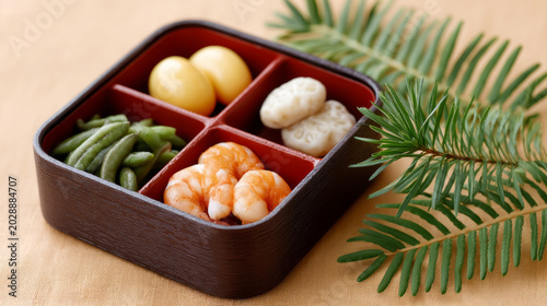 Traditional japanese osechi bento box with shrimp, beans, and pine leaf decoration for new year celebration