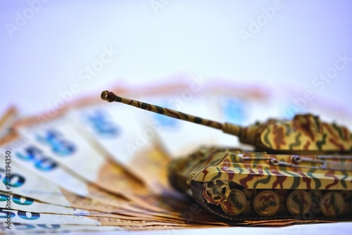 Toy tank on euro banknotes symbolizing military spending and defense budget in Europe