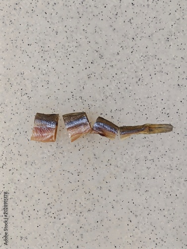 Quadro su tela Salty dried smelt fish pieces meticulously arranged on a speckled light gray and