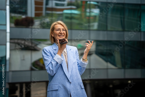 Valokuva Mature woman communicating with smartphone using voice assistant