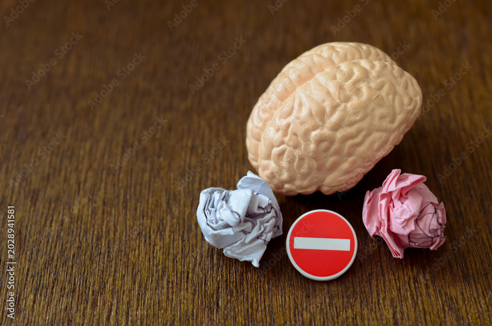 Fototapeta premium Behavioral correction and mental self-restraint concept showing a brain model with a tiny traffic stop sign and crumpled paper balls