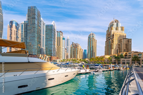 Futuristic skyscrapers rise above waterfront commercial storefronts and luxury  marinas at the Dubai Marina, in Dubai, United Arab Emirates.