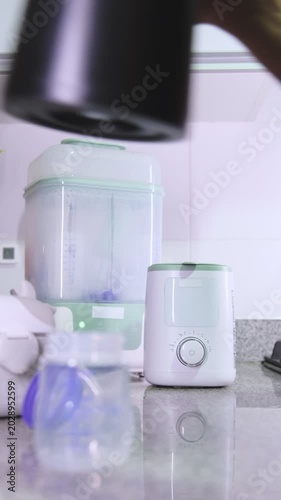 Man's hands pouring water and powdered milk into a baby bottle in the kitchen at home