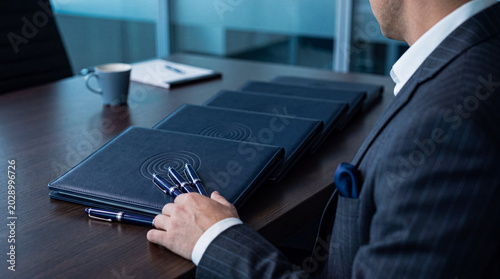 Photos Professional businessman with organized blue folders and pens on a sleek conference table, ready for a meeting