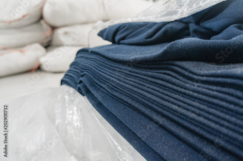 Stack of dark blue fabric rolls in a textile factory storage, clothing background with copy space