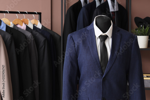 Foto Shelving unit, rack and mannequin with different stylish male suits in dressing