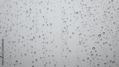 Cinematic rain droplets on glass wall in gray color