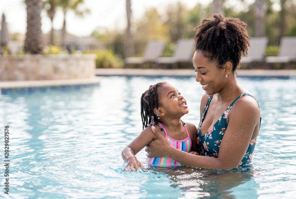 Fototapeta premium African american mother gently teaching her young daughter to swim in a bright outdoor pool