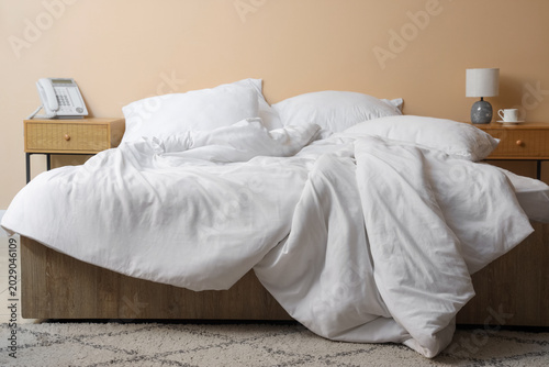 Foto Interior of hotel room with bedside tables, unmade bed and crumpled linen near b