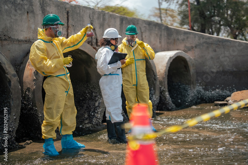 Obraz na plátně Scientists collecting polluted liquid samples from contaminated drainage canal to evaluate industrial wastewater toxicity and environmental damage in coastal ecosystem area