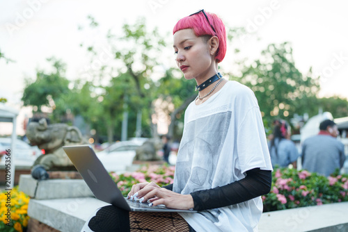 Gen z girl leather fashion with punk Asian woman working remotely on laptop digital nomad in Thailand