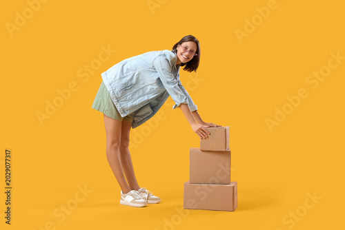 Beautiful young happy woman with parcels on yellow background