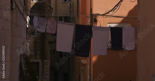 Laundry hanging on clotheslines between buildings in a narrow old town street.