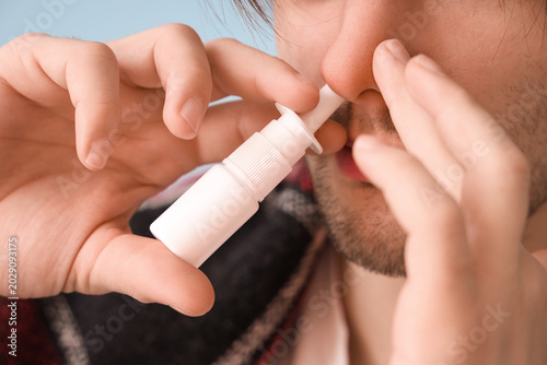 Obraz na płótnie Ill young man with nasal drops at home