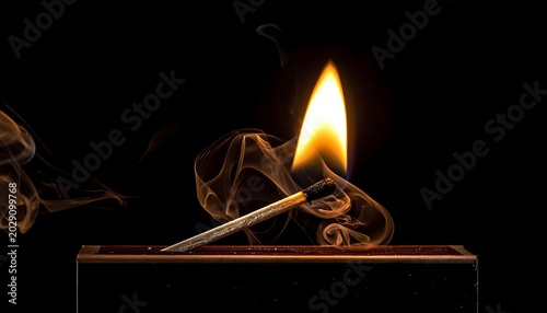 A lit matchstick on a matchbox with smoke rising