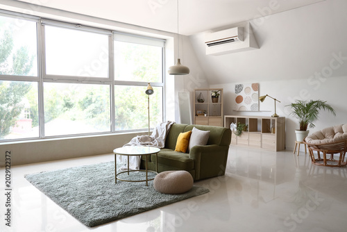 Interior of light living room with green armchair, coffee table and standard lamp