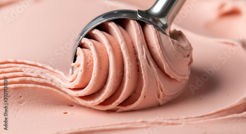 Scooping pink ice cream with metal spoon