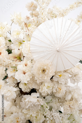 Detail with white japanese vibe umbrela, Elegant white flowers cascade upward in graceful tiers. Delicate blooms and soft petals frame a clean, minimalist backdrop. Neutral tones enhance purity