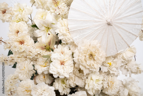 Detail with white japanese vibe umbrela, Elegant white flowers cascade upward in graceful tiers. Delicate blooms and soft petals frame a clean, minimalist backdrop. Neutral tones enhance purity