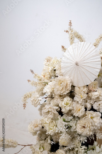 Detail with white japanese vibe umbrela, Elegant white flowers cascade upward in graceful tiers. Delicate blooms and soft petals frame a clean, minimalist backdrop. Neutral tones enhance purity