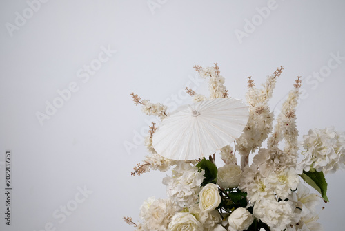 Detail with white japanese vibe umbrela, Elegant white flowers cascade upward in graceful tiers. Delicate blooms and soft petals frame a clean, minimalist backdrop. Neutral tones enhance purity