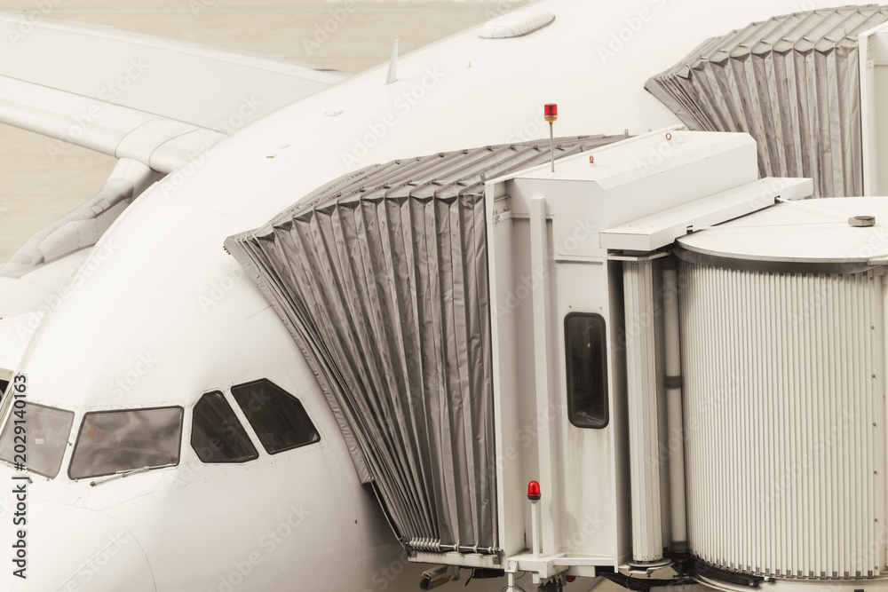 Obraz premium Passenger boarding bridge connected to aircraft at airport terminal