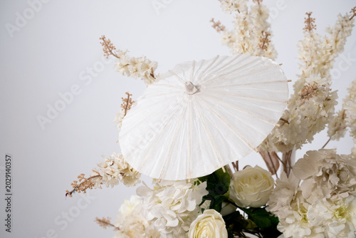 Detail with white japanese vibe umbrela, Elegant white flowers cascade upward in graceful tiers. Delicate blooms and soft petals frame a clean, minimalist backdrop. Neutral tones enhance purity