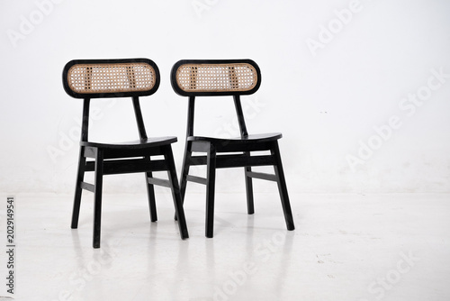 Warm wooden chairs with woven cane backs. Curved seats and slender legs create elegant design. Simple, minimalist style suits modern interiors. Ideal for cafes, homes, or cozy dining spaces.