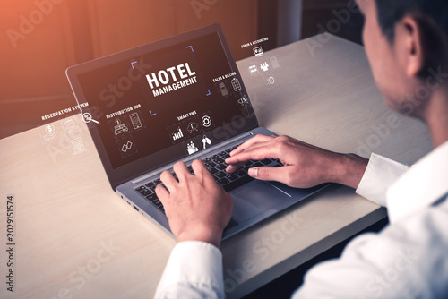 Professional individual engaged in hotel management using laptop with digital interface showcasing different hotel management features and tools Quark.