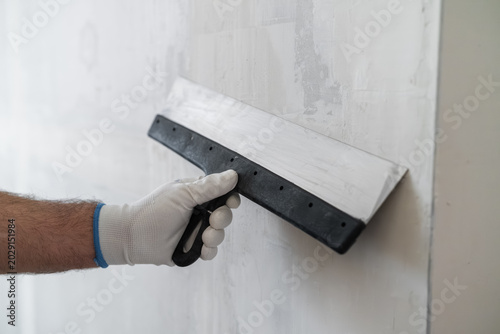 Tableau sur toile A professional is smoothing joint compound on a drywall surface using a hand trowel