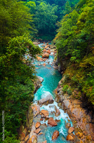 Vibrant turquoise water of Rimbi River flowing over orange boulders in West Sikkim,
India
