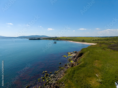 Coastal view with clear water and green land near the beach